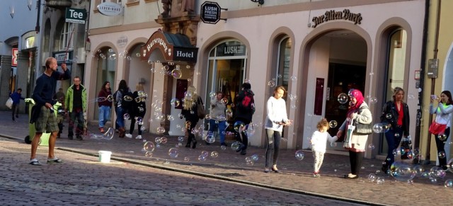 man blowing bubbles on city street